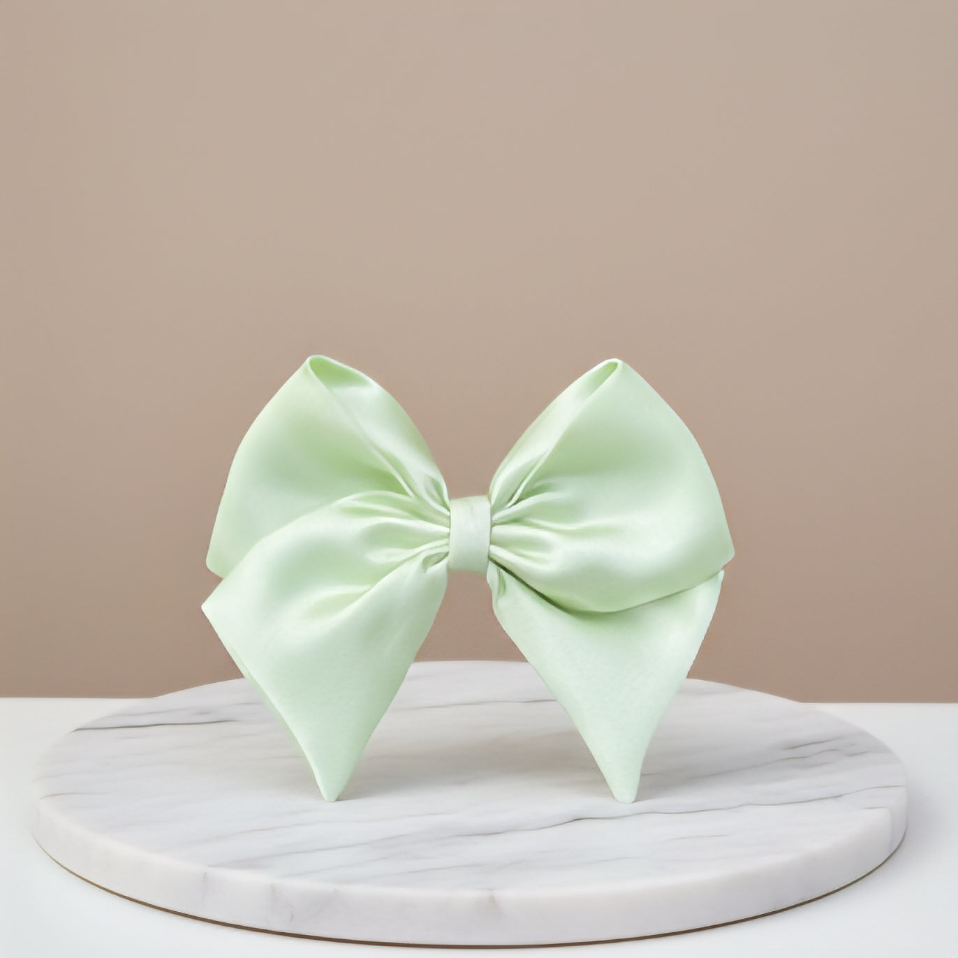 Light green bow on a marble stand with a beige background